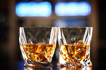 Glasses of whiskey on bar background