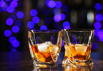 Glasses of whiskey on bar background
