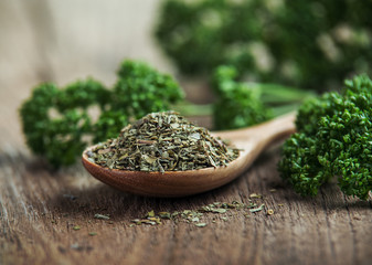 dried parsley in wooden spoon on old wooden