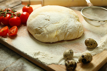 Dough on cutting board with cherry and quail eggs on table close up