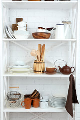 Fototapeta na wymiar Kitchen shelving with dishes on white brick wall background