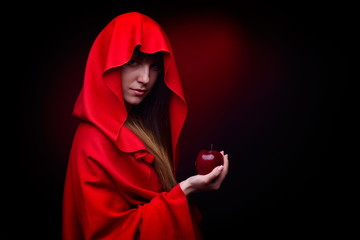 beautiful woman with red cloak holding apple - studio shot
