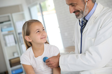 Doctor examining young girl with stethoscope