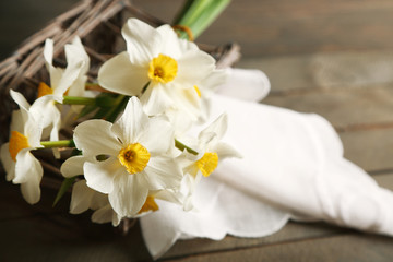 Obraz premium Fresh narcissus with wicker basket on wooden background