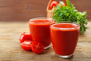 Glasses of fresh tomato juice on wooden background