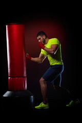 young man standing exercising with  boxing bag in studio