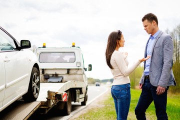 Couple near tow-truck picking up broken car