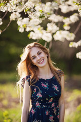 happy young lady standing in blooming tree