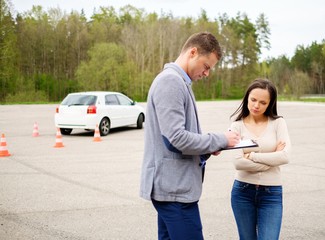 Driving instructor and woman student in examination area