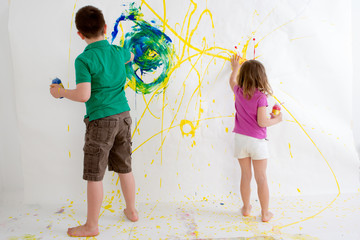 Fototapeta premium Two young children freehand painting on a wall