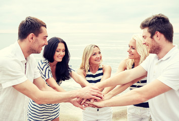 Obraz premium smiling friends putting hands on top of each other