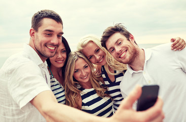 happy friends on beach and taking selfie