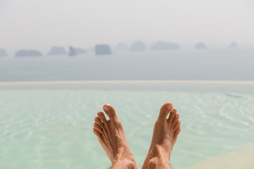 closeup of male feet over sea and sky on beach