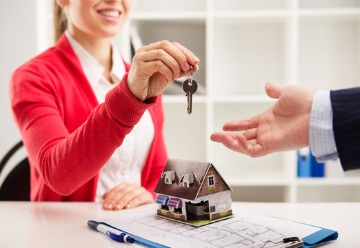 Smiling woman realtor giving key of new apartment to client
