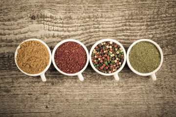White ceramic cups with different kinds of spices on old wooden