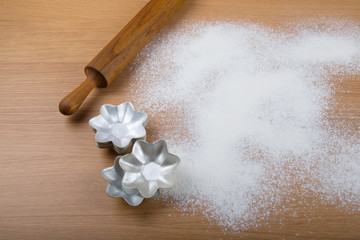 Rolling pin, forms for baking and flour sprinkled on a light woo