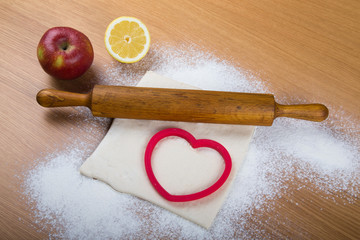 Set for home baking on a light wooden table with flour. Rolling