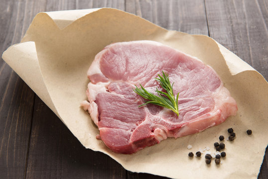 raw pork chop steak on paper and wooden background