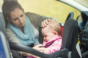 Mother and her little baby girl in a child seat in a car