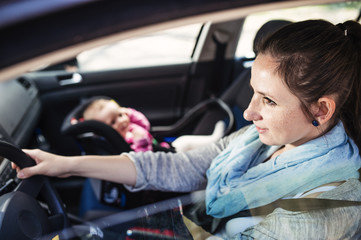 Mother and her little baby girl in a child seat in a car