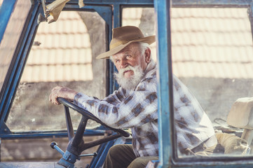 Senior man at the farm driving an old tractor
