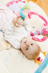 portrait of baby girl lying on playing mat