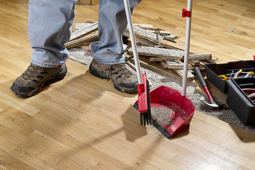An unrecognizable person with a broom sweeping floor. - obrazy, fototapety, plakaty