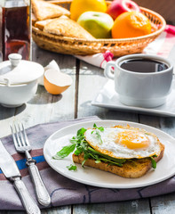 crispy toast with a fried egg and green arugula, coffee cup, fru