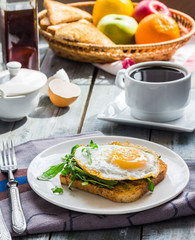 crispy toast with a fried egg and green arugula, coffee cup, fru