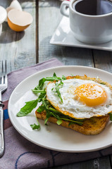 crispy toast with a fried egg and green arugula, coffee cup, fru