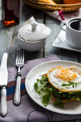 crispy toast with a fried egg and fresh arugula, a cup of coffee