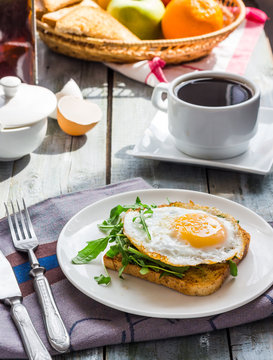 crispy toast with a fried egg and green arugula, coffee cup, fru