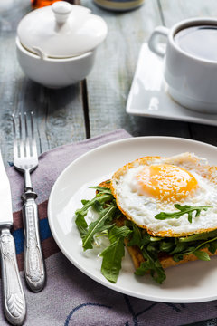 crispy toast with a fried egg and fresh arugula, a cup of coffee