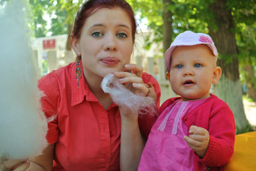 Young mother with baby girl eating cotton candy in the Park