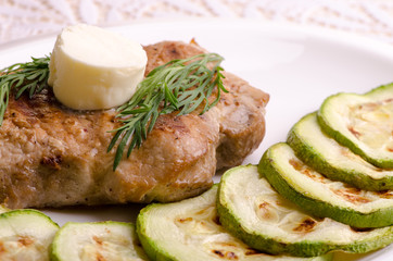 Juicy pork with melting butter and zucchini slices, close-up