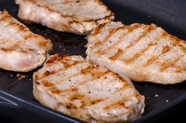 grilled pork steak in a frying pan during cooking