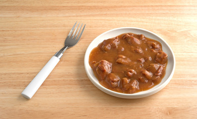 Roast beef in gravy with fork on table