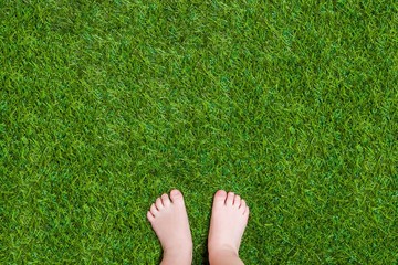 Baby legs standing  on green summer grass 