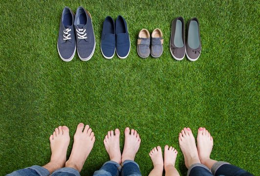Family legs in jeans and shoes standing  on grass