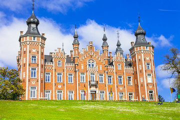 Obraz premium Springtime at de Viron Castle Dilbeek. Flemish architecture with blooming tulips and green lawn. Historic Belgian chateau in a sunny park. Royal heritage scenery. No people daytime 5K background