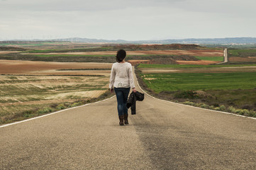 Woman walking alone in a country road - 82770105