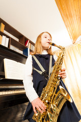 Girl in school uniform playing on alto saxophone