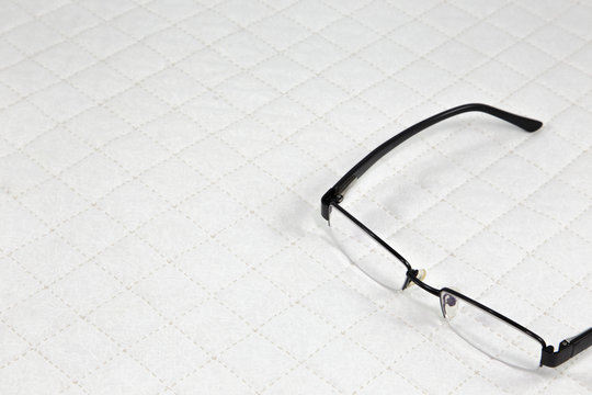 eyeglasses put on white patchwork Quilt background