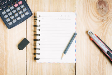 Notebook paper and school or office tools on vintage wood table