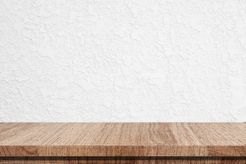 Empty wooden table over white cement wall background