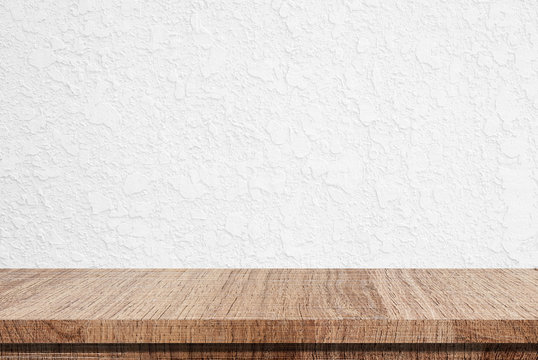 Empty wooden table over white cement wall background