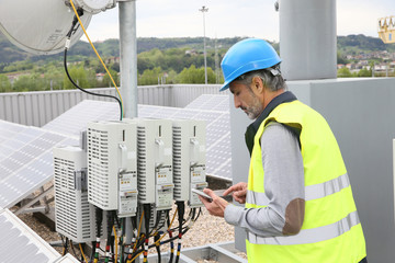 Mature engineer on building roof checking solar panels