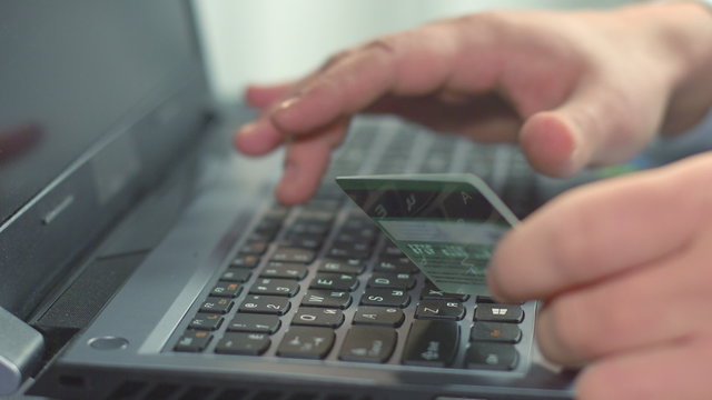 Closeup of male hand inserting bank card number, shopping online