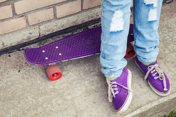 Teenager in gumshoes stands with skateboard
