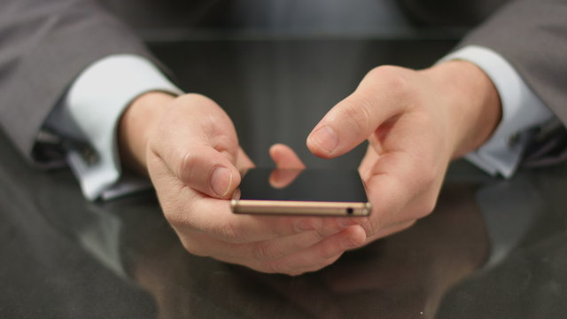 Boss using expensive smartphone, thumb touching screen closeup
